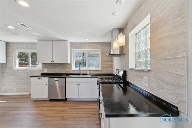 3105 W Laskey Rd, Toledo, OH 43613 - kitchen featuring dark countertops, visible vents, wall chimney range hood, a sink, and appliances with stainless steel finishes