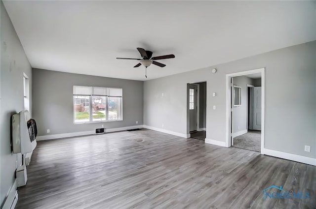 221 S Cherry St, Paulding, OH 45879 - unfurnished living room with baseboards, a ceiling fan, heating unit, and wood finished floors