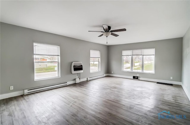 221 S Cherry St, Paulding, OH 45879 - unfurnished living room featuring heating unit, wood finished floors, visible vents, a ceiling fan, and baseboards