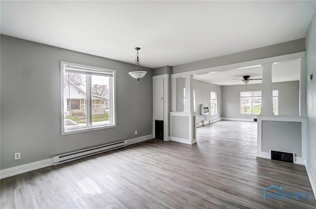 221 S Cherry St, Paulding, OH 45879 - unfurnished dining area with a baseboard heating unit, plenty of natural light, a ceiling fan, and ornate columns