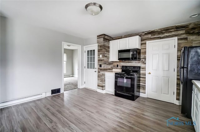 221 S Cherry St, Paulding, OH 45879 - kitchen with a baseboard heating unit, black appliances, dark wood-type flooring, and visible vents