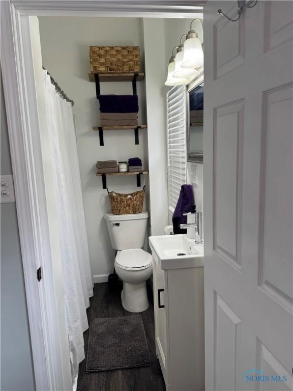 full bath with toilet, wood finished floors, vanity, and baseboards
