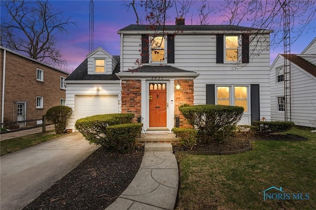 traditional-style home featuring concrete driveway, a front lawn, a chimney, a shingled roof, and a garage