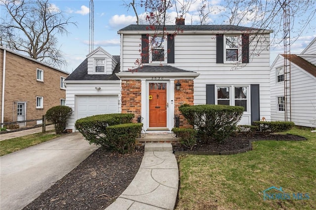 traditional-style house with concrete driveway, a garage, a shingled roof, and a front yard
