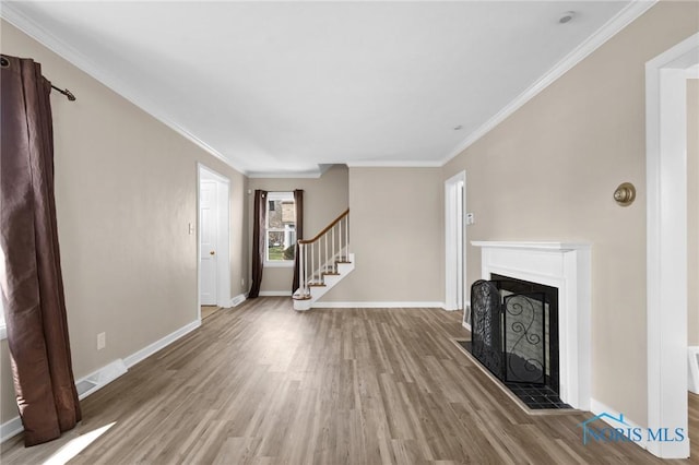 unfurnished living room with baseboards, a fireplace with raised hearth, wood finished floors, stairs, and ornamental molding