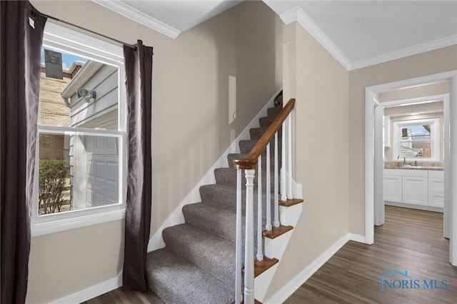 staircase with baseboards, ornamental molding, and wood finished floors