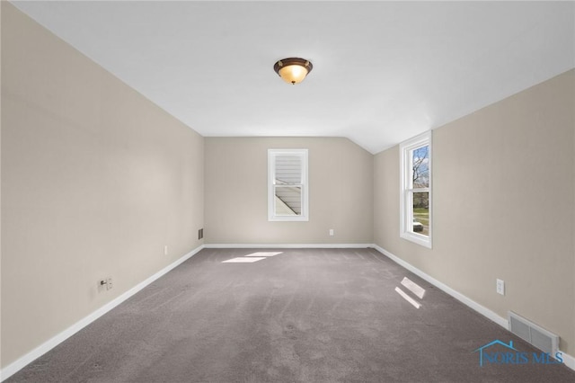 additional living space featuring vaulted ceiling, carpet floors, visible vents, and baseboards