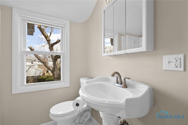 bathroom with toilet, a sink, and baseboards