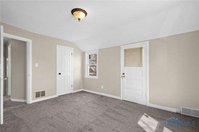 unfurnished room with baseboards, vaulted ceiling, visible vents, and carpet flooring