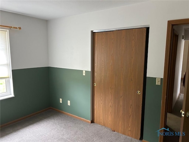 unfurnished bedroom with a closet, carpet flooring, and baseboards