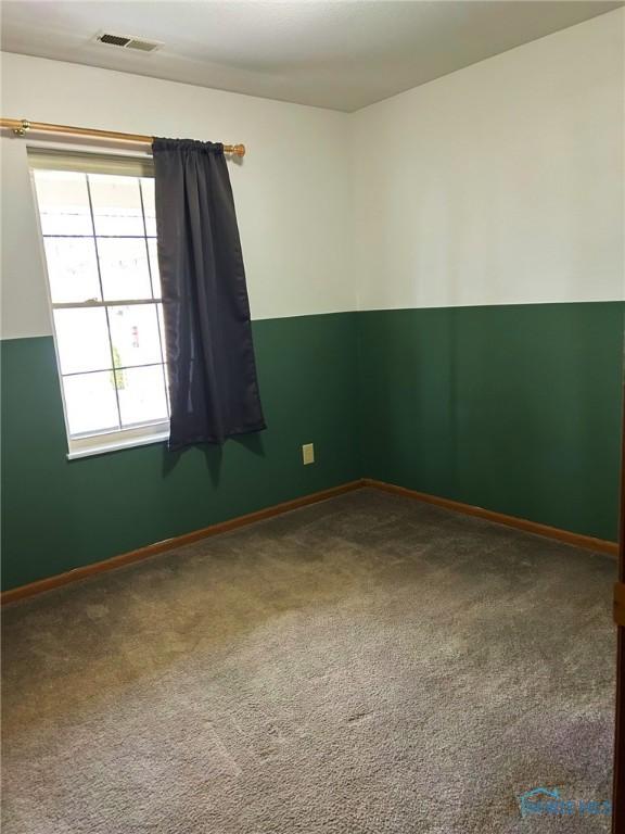 carpeted spare room with baseboards and visible vents