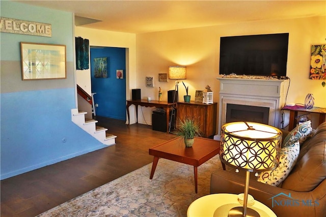 living room with a fireplace, wood finished floors, baseboards, and stairway