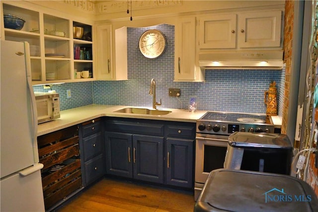 kitchen with a sink, decorative backsplash, white appliances, light countertops, and under cabinet range hood