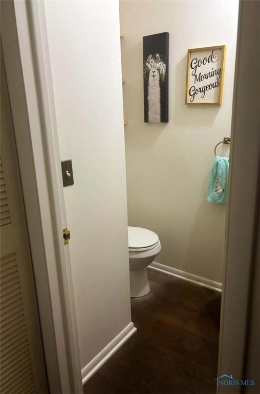 bathroom with wood finished floors, baseboards, and toilet