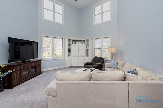 carpeted living room with a high ceiling and baseboards