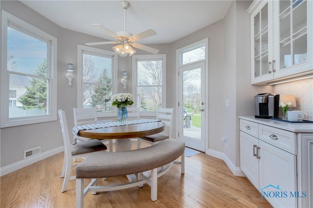 dining space featuring visible vents, light wood finished floors, baseboards, and ceiling fan