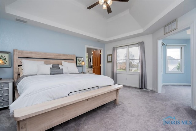 carpeted bedroom featuring a raised ceiling, visible vents, a ceiling fan, and baseboards