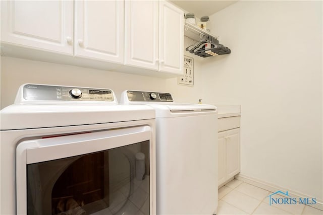 laundry area featuring baseboards, washing machine and clothes dryer, cabinet space, and light tile patterned floors