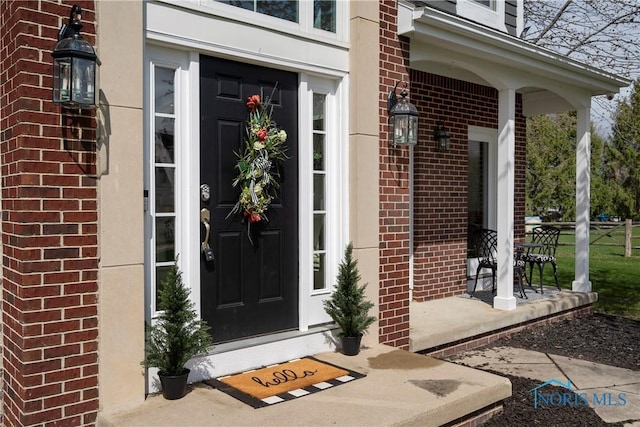 doorway to property with brick siding and a porch