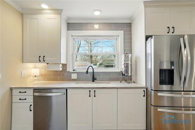 kitchen featuring stainless steel appliances, backsplash, ornamental molding, a sink, and light stone countertops