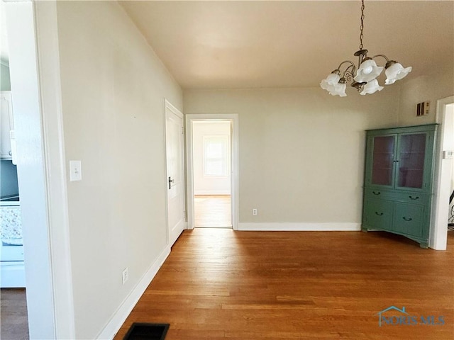 440 Union Ct, Fostoria, OH 44830 - unfurnished dining area featuring a chandelier, wood finished floors, visible vents, and baseboards