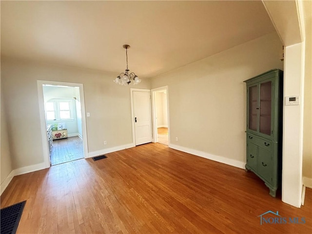440 Union Ct, Fostoria, OH 44830 - unfurnished dining area with a chandelier, wood finished floors, visible vents, and baseboards
