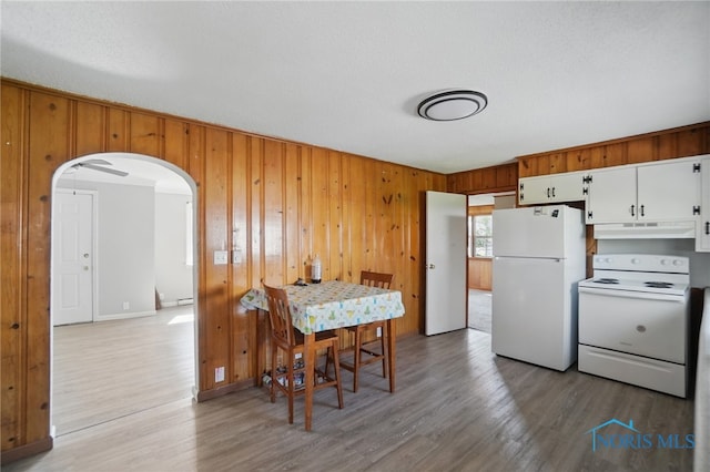402 S 5th St, Continental, OH 45831 - kitchen featuring light wood-style flooring, wood walls, arched walkways, under cabinet range hood, and white appliances