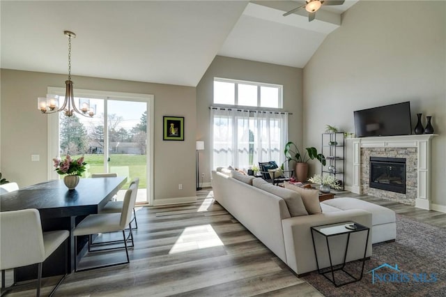 1007 Stoneleigh Rd, Perrysburg, OH 43551 - living area featuring baseboards, ceiling fan with notable chandelier, wood finished floors, a stone fireplace, and high vaulted ceiling