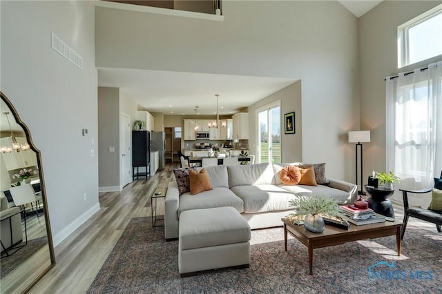 1007 Stoneleigh Rd, Perrysburg, OH 43551 - living room with light wood-style flooring, visible vents, a notable chandelier, and a high ceiling