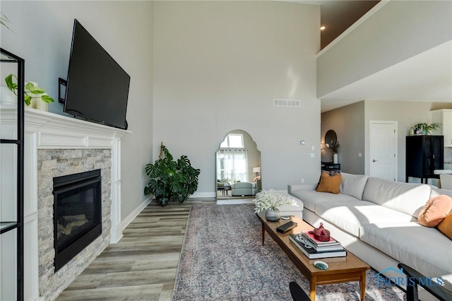 1007 Stoneleigh Rd, Perrysburg, OH 43551 - living area featuring a stone fireplace, light wood-style floors, arched walkways, a towering ceiling, and visible vents