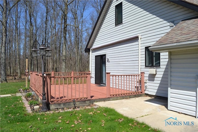 view of side of home with a wooden deck and roof with shingles