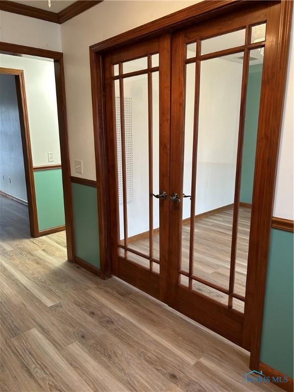 doorway to outside featuring wood finished floors, baseboards, ornamental molding, and french doors
