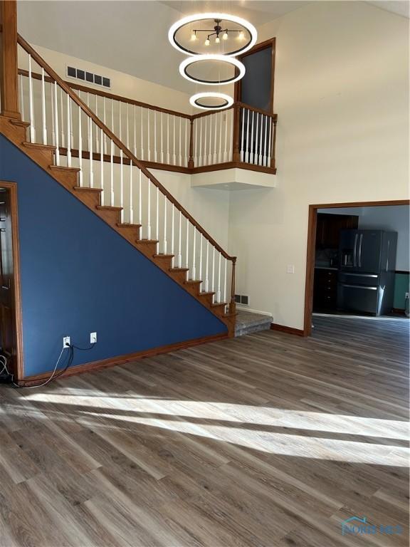 unfurnished living room with a high ceiling, wood finished floors, and visible vents
