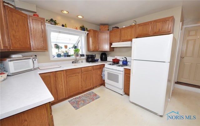 kitchen with a sink, white appliances, brown cabinetry, light countertops, and under cabinet range hood