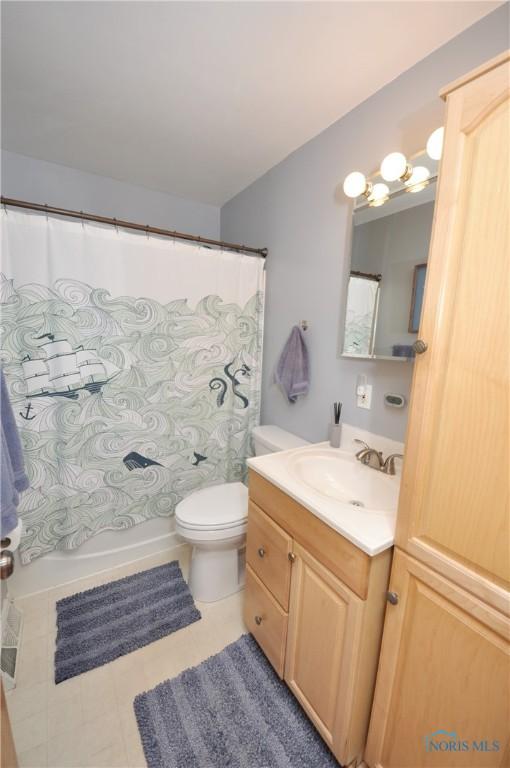 bathroom with toilet, vanity, and shower / bath combination with curtain