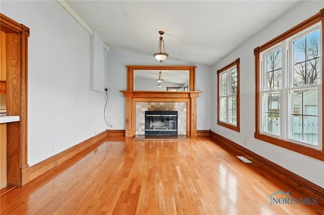 1000 Washington Ave, Findlay, OH 45840 - unfurnished living room featuring light wood-style flooring, vaulted ceiling, a tiled fireplace, and baseboards
