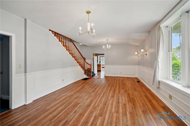 1000 Washington Ave, Findlay, OH 45840 - unfurnished living room with a chandelier, stairs, wood finished floors, a decorative wall, and healthy amount of natural light