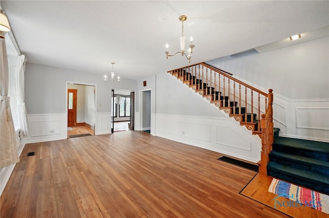 1000 Washington Ave, Findlay, OH 45840 - unfurnished living room with a chandelier, stairway, wood finished floors, a decorative wall, and wainscoting