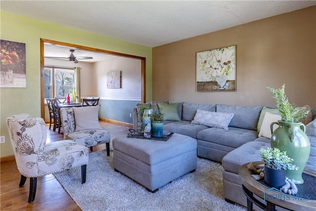 living room with baseboards, wood finished floors, and ceiling fan
