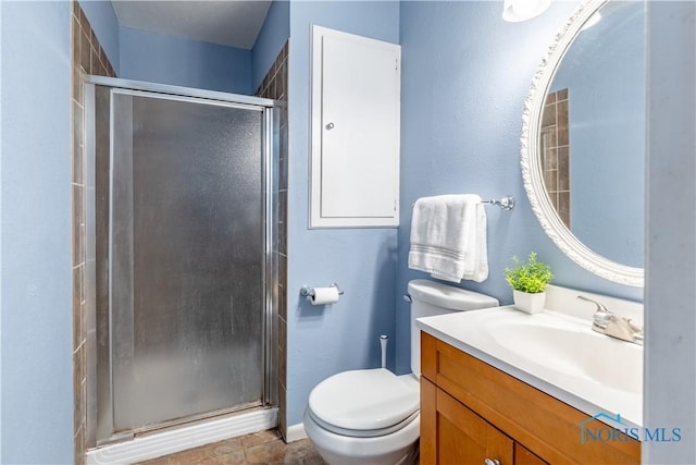 bathroom featuring baseboards, vanity, a shower stall, and toilet