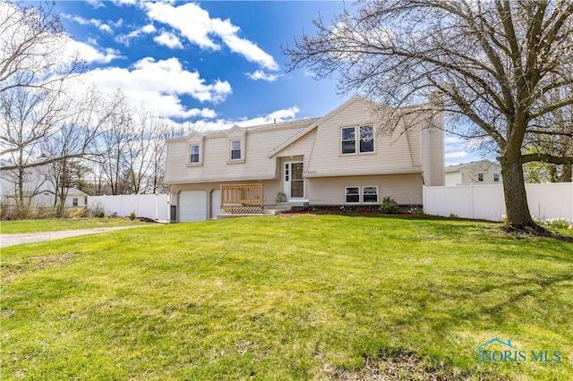 bi-level home featuring a garage, driveway, a front yard, and fence