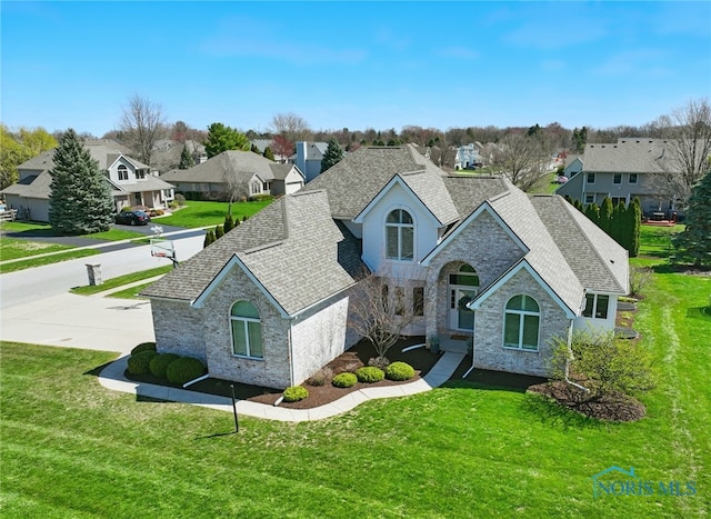 view of front of house featuring a front lawn, roof with shingles, a residential view, and stone siding