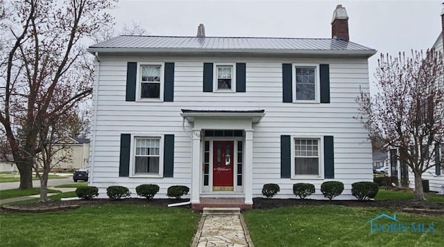 740 E Main St, Ottawa, OH 45875 - colonial-style house featuring a front yard, a chimney, and metal roof