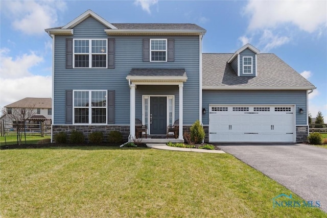 view of front of house featuring aphalt driveway, fence, an attached garage, stone siding, and a front yard