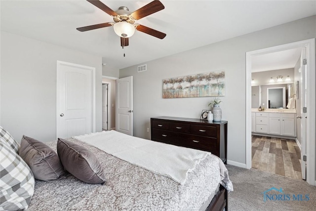 bedroom with light carpet, visible vents, baseboards, a ceiling fan, and connected bathroom