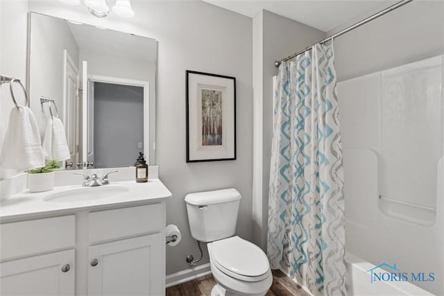 bathroom featuring baseboards, wood finished floors, toilet, and vanity