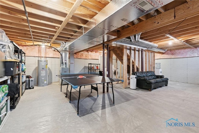 playroom with water heater, unfinished concrete flooring, and heating unit
