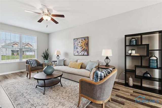 living room with ceiling fan, baseboards, and wood finished floors