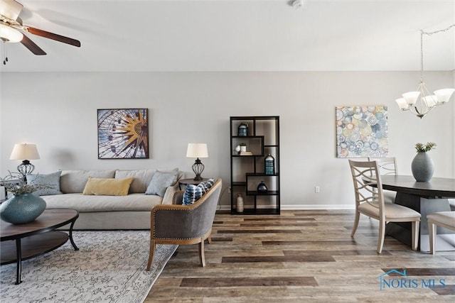 living area with wood finished floors, baseboards, and ceiling fan with notable chandelier