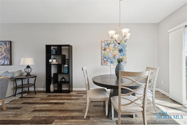 dining area with baseboards, a notable chandelier, and wood finished floors
